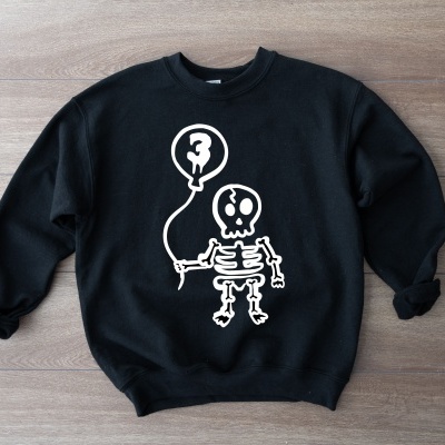 Sweatshirt preta com desenho branco de esqueleto segurando balão