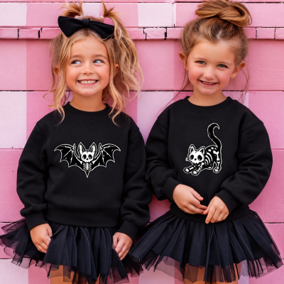 Duas meninas com sweatshirts pretas de morcego e gato esqueleto de Halloween