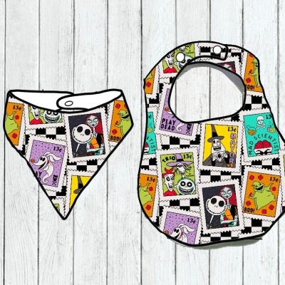 Dois aventais para bebé coloridos com estampado de selos Halloween sobre fundo de madeira branca