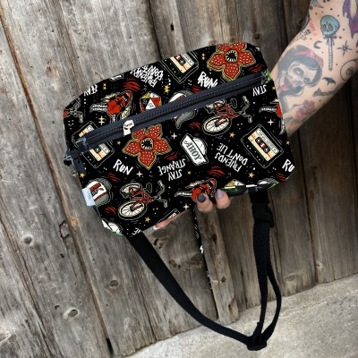 Bolsa de cintura preta com padrão colorido e fecho de correr