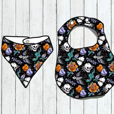 Babete e bandana para bebé com padrão colorido de caveiras, flores, corações e fantasmas sobre fundo preto