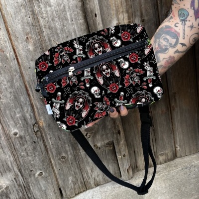 Bolsa pochete preta com padrão de palhaços e rosas, com fechos de correr azuis e alça preta