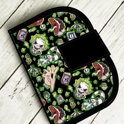 Carteira preta com estampado cartoon colorido sobre superfície de madeira branca