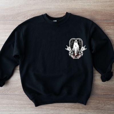 Camisola preta com estampa pequena branca e vermelha no peito sobre fundo de madeira clara