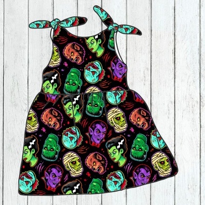 Vestido infantil preto com padrão colorido de cabeças de monstros e alças de amarrar nos ombros