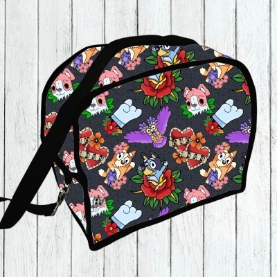 Mala pequena preta com padrão colorido de tatuagens e desenhos cartoon sobre fundo de madeira branca