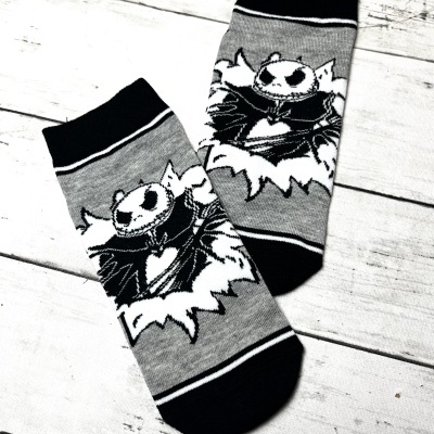 Meias cinzentas com estampa de personagem preto e branco sobre fundo de madeira