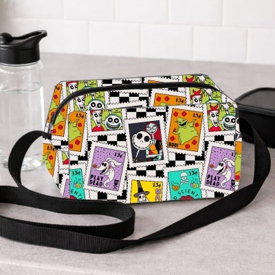 Mala pequena colorida com padrão de selos postais e acessórios num balcão