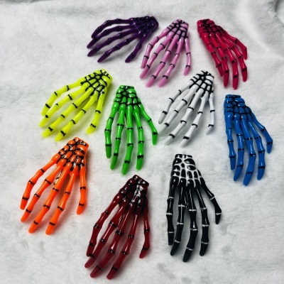 Presilhas de cabelo em forma de mãos esqueléticas coloridas sobre superfície branca