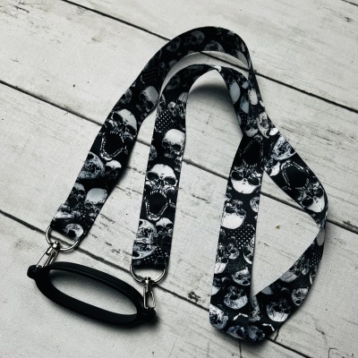 Cordão para óculos preto com padrão de caveiras e suporte metálico
