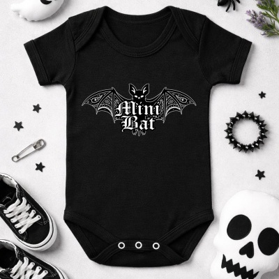 Body preto para bebé com desenho de morcego e texto Mini Bat, acessórios de Halloween à volta.