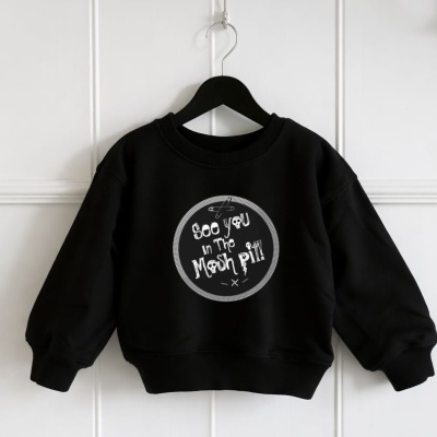 Sweatshirt preta de criança com padrão branco e texto em frente, pendurada num cabide