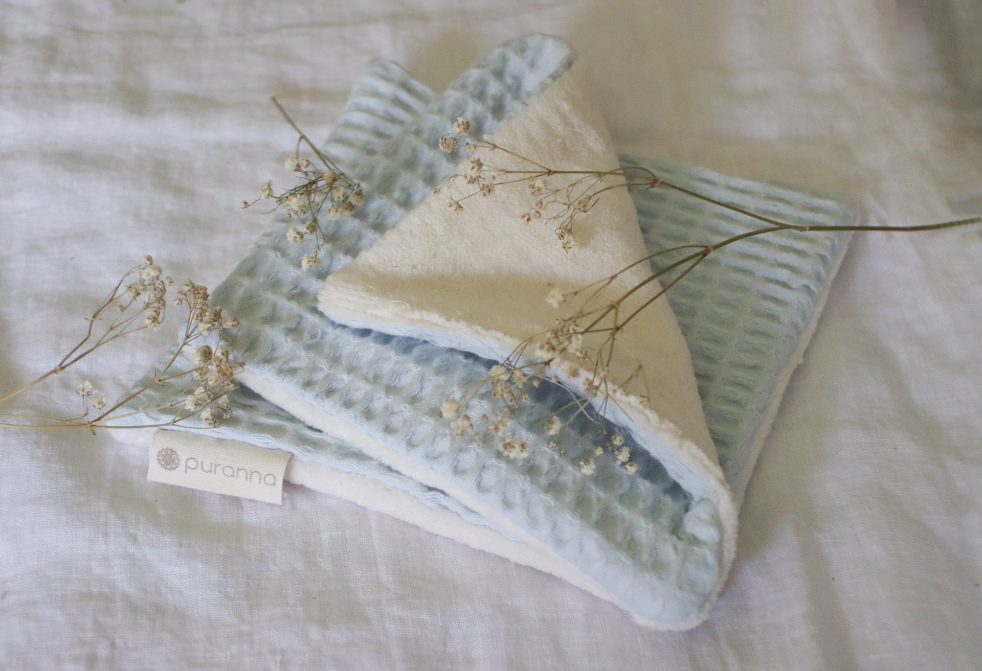 Toalha pequena azul claro com lado creme e raminhos secos