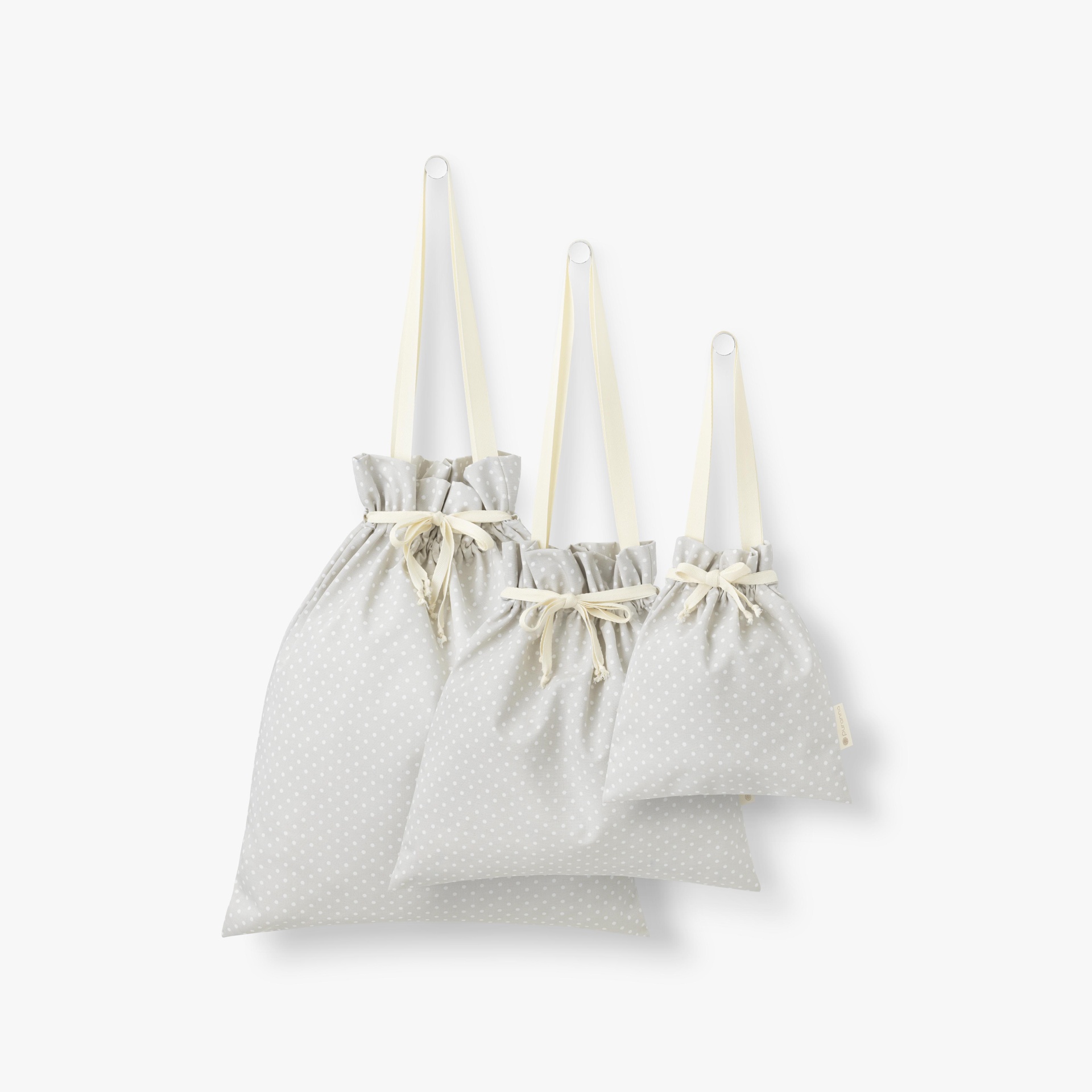Conjunto de três sacos de tecido cinza claro com padrões de pontos brancos e cordões creme