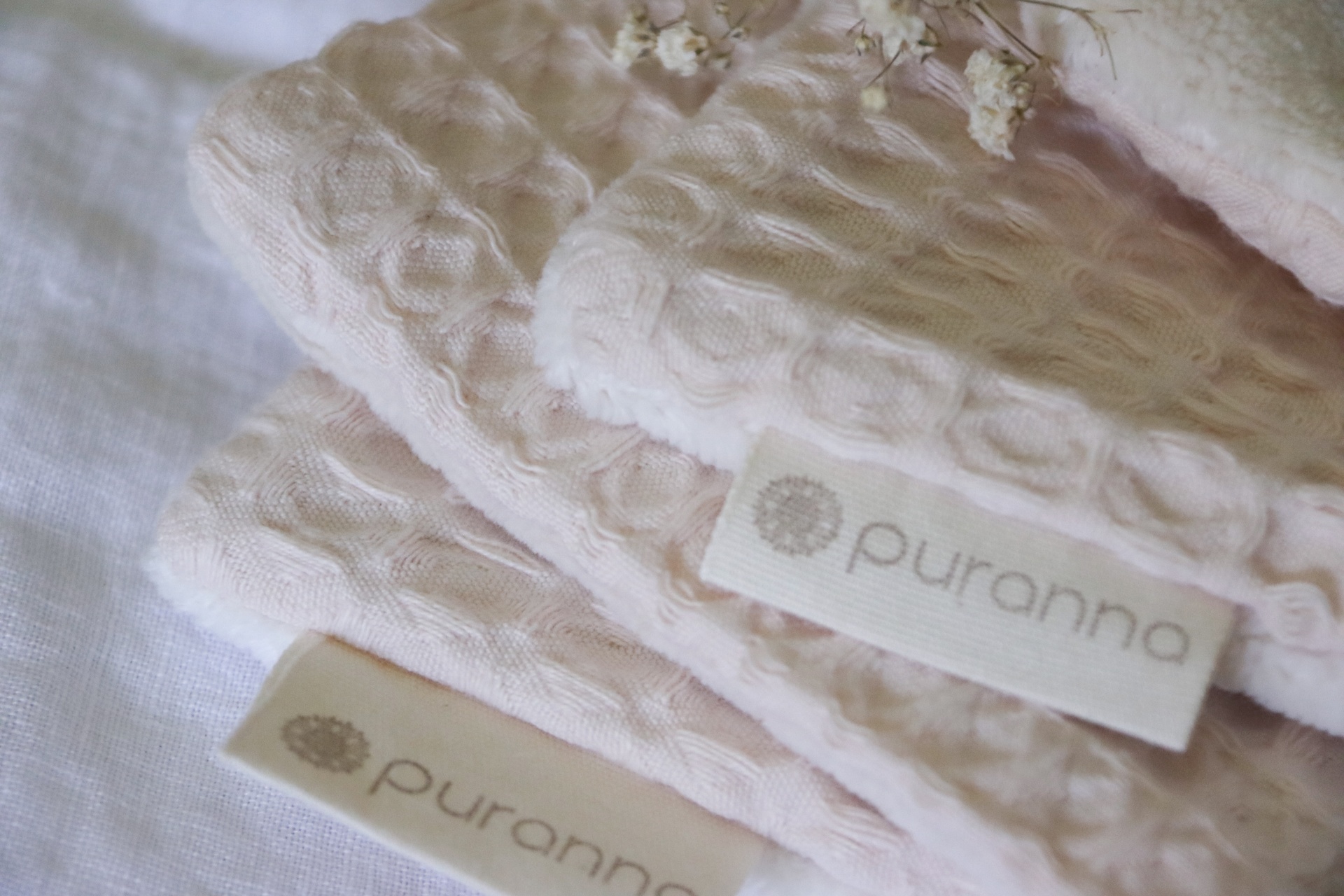 panos ou toalhas cor rosa claro com etiquetas puranna sobre tecido branco
