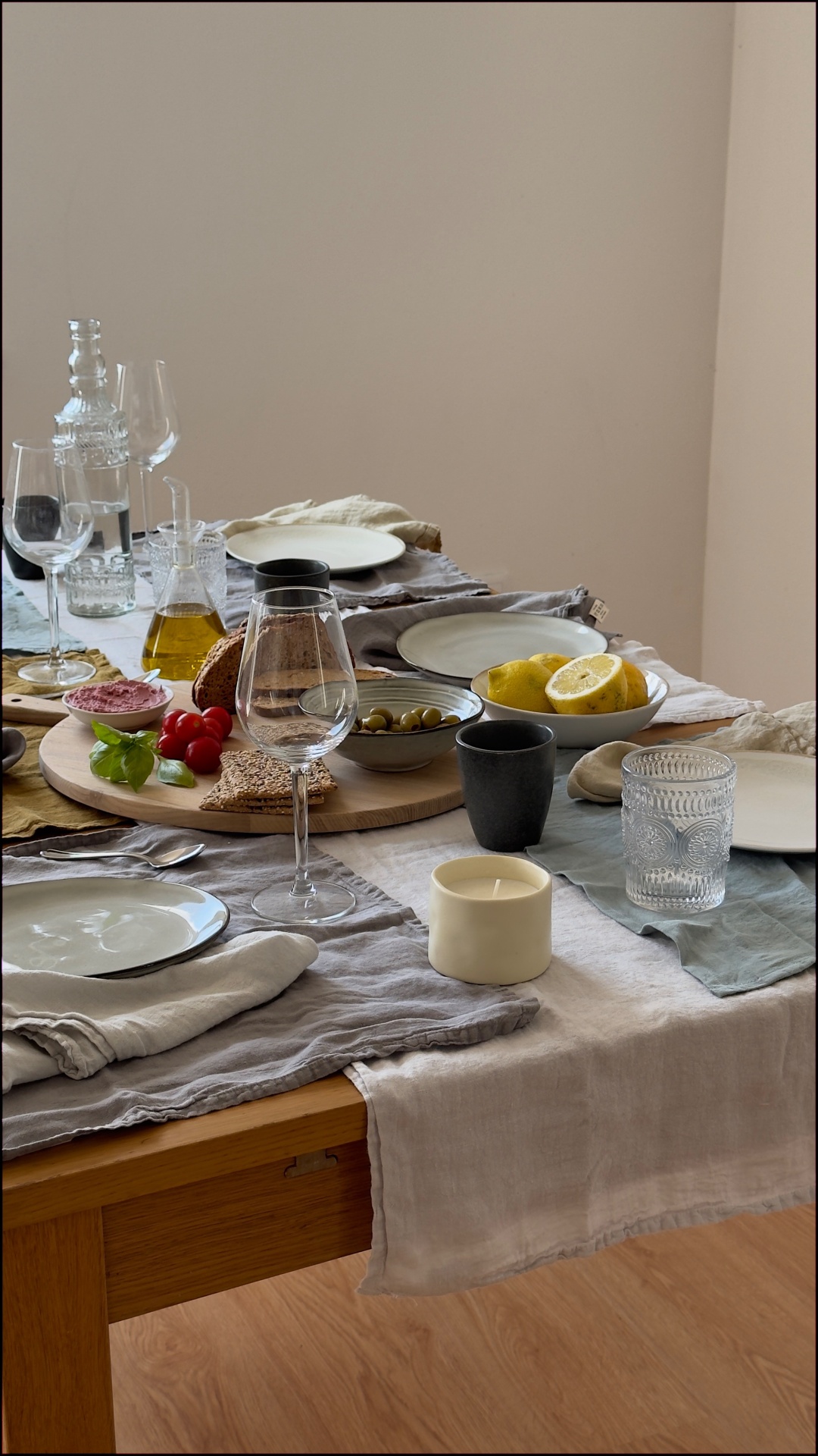 Mesa posta com pratos, copos, taças, comida e decoração em tons neutros