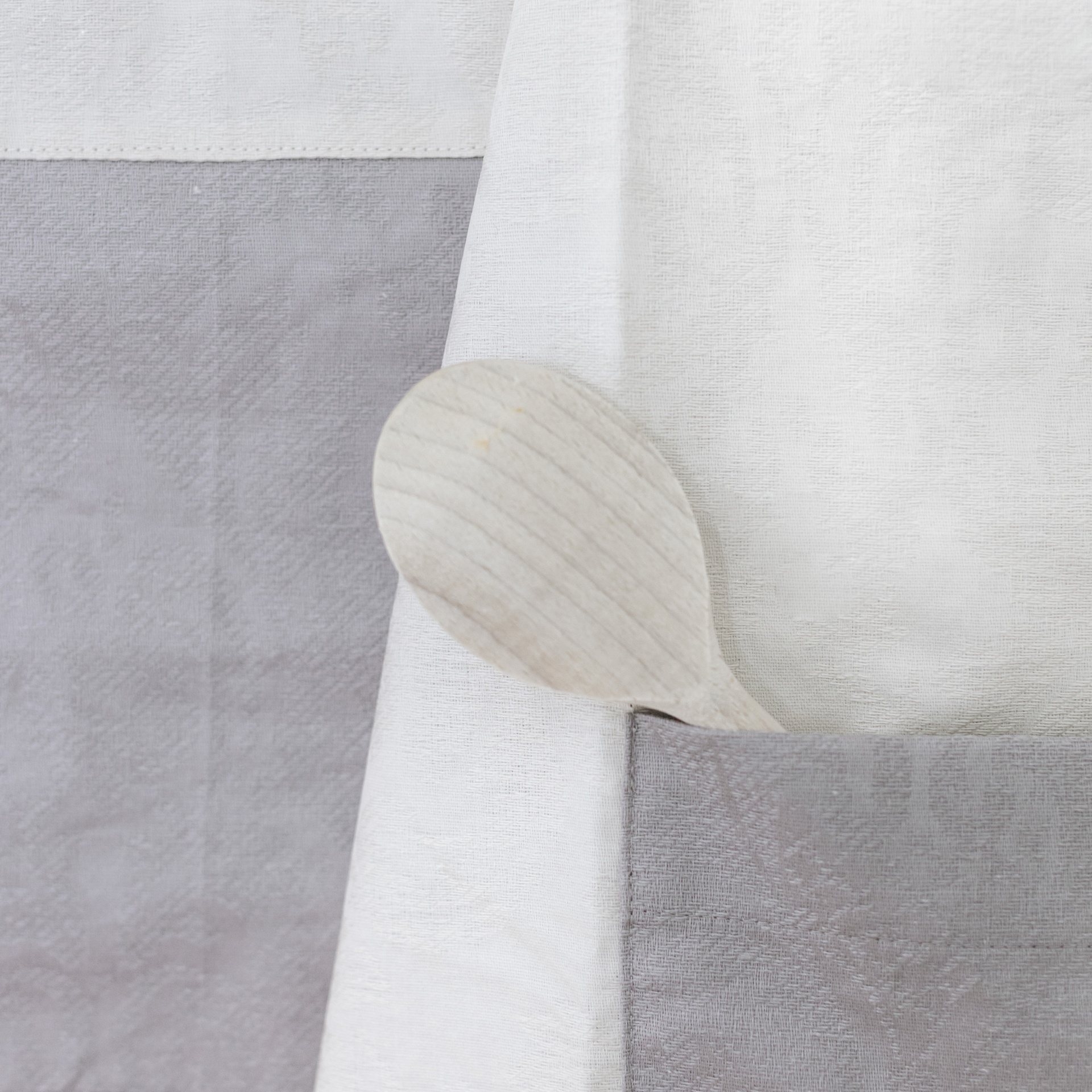 Avental branco e cinzento com colher de pau no bolso cinzento