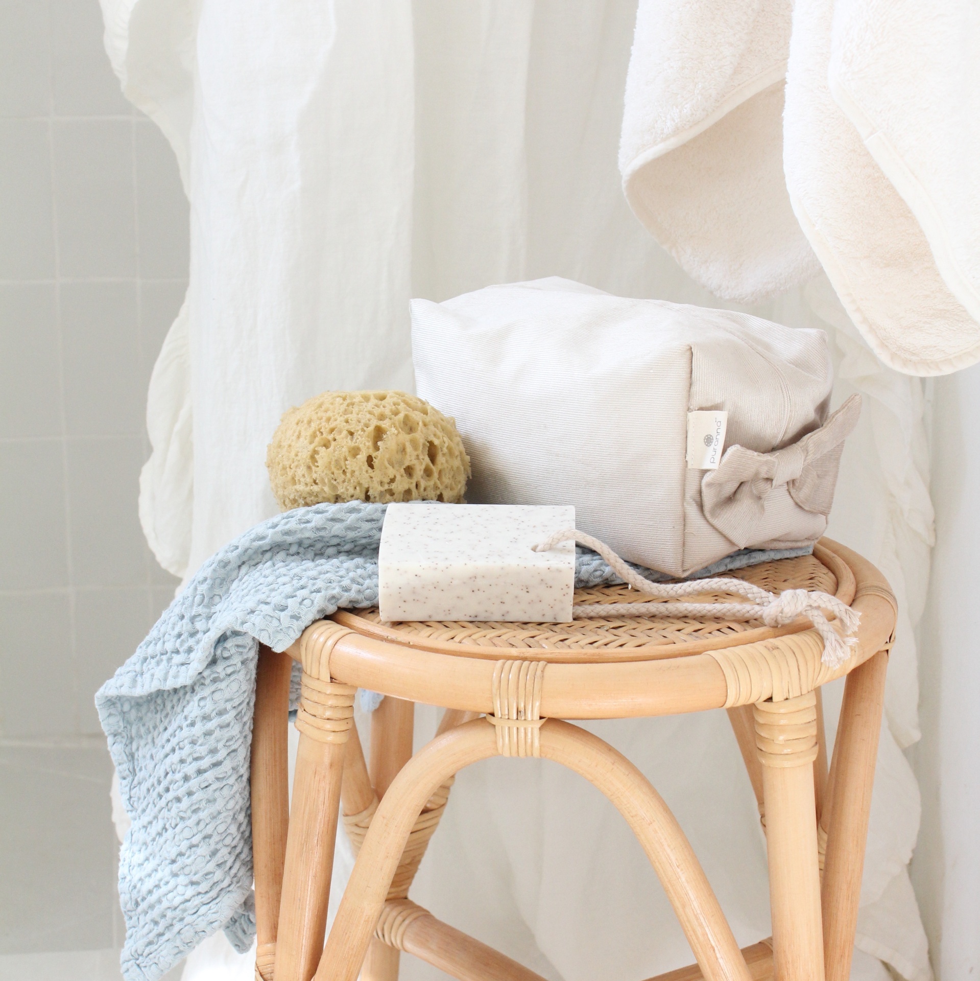 Mesa em vime com itens de higiene e toalhas em tecido azul e branco
