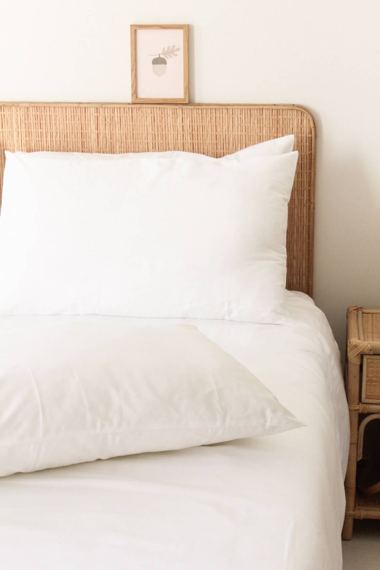 Cama com cabeceira e mesa de cabeceira em rattan e roupa de cama branca