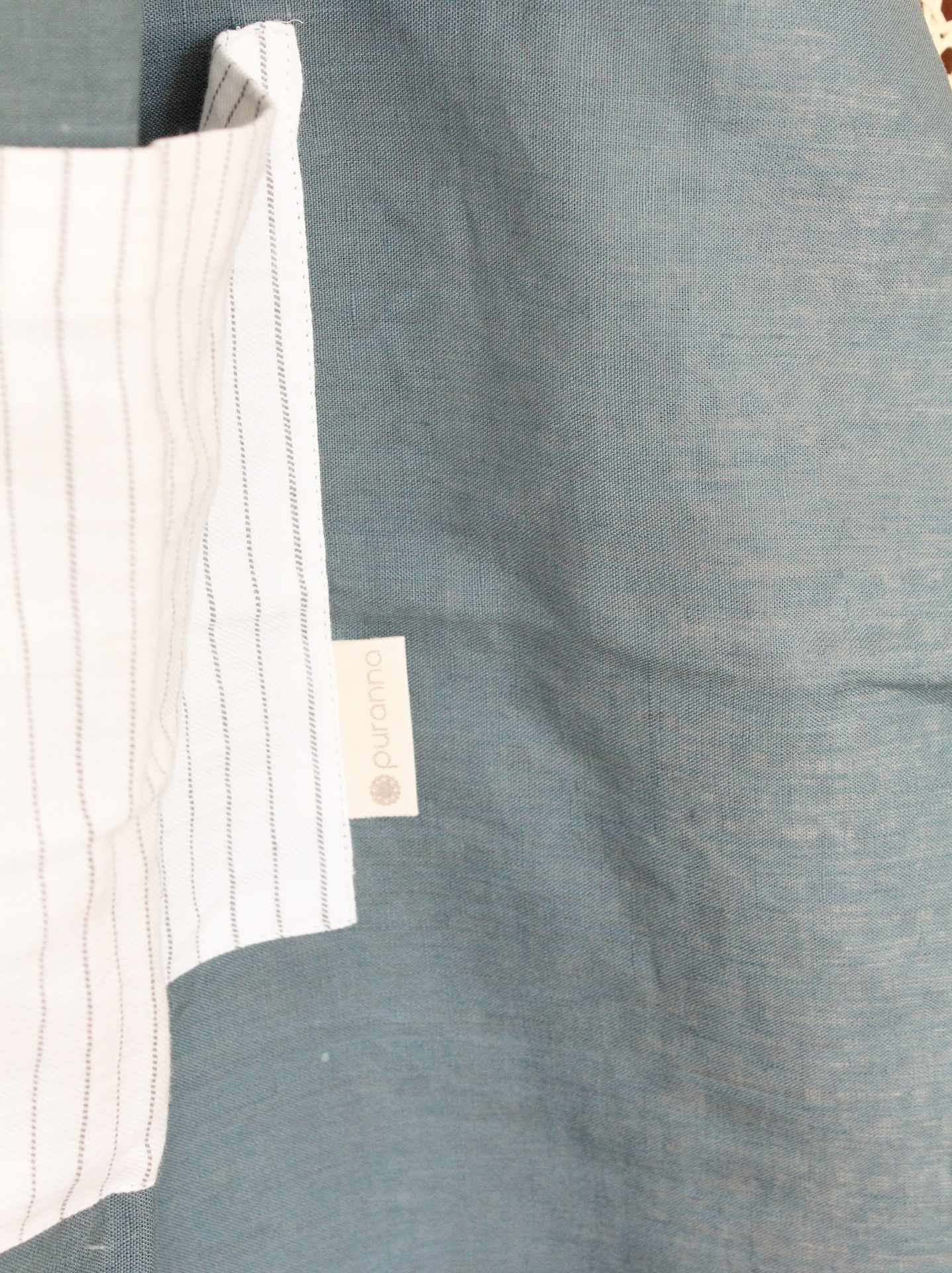 Lençol branco riscado com etiqueta QUOAMA sobre superfície azul