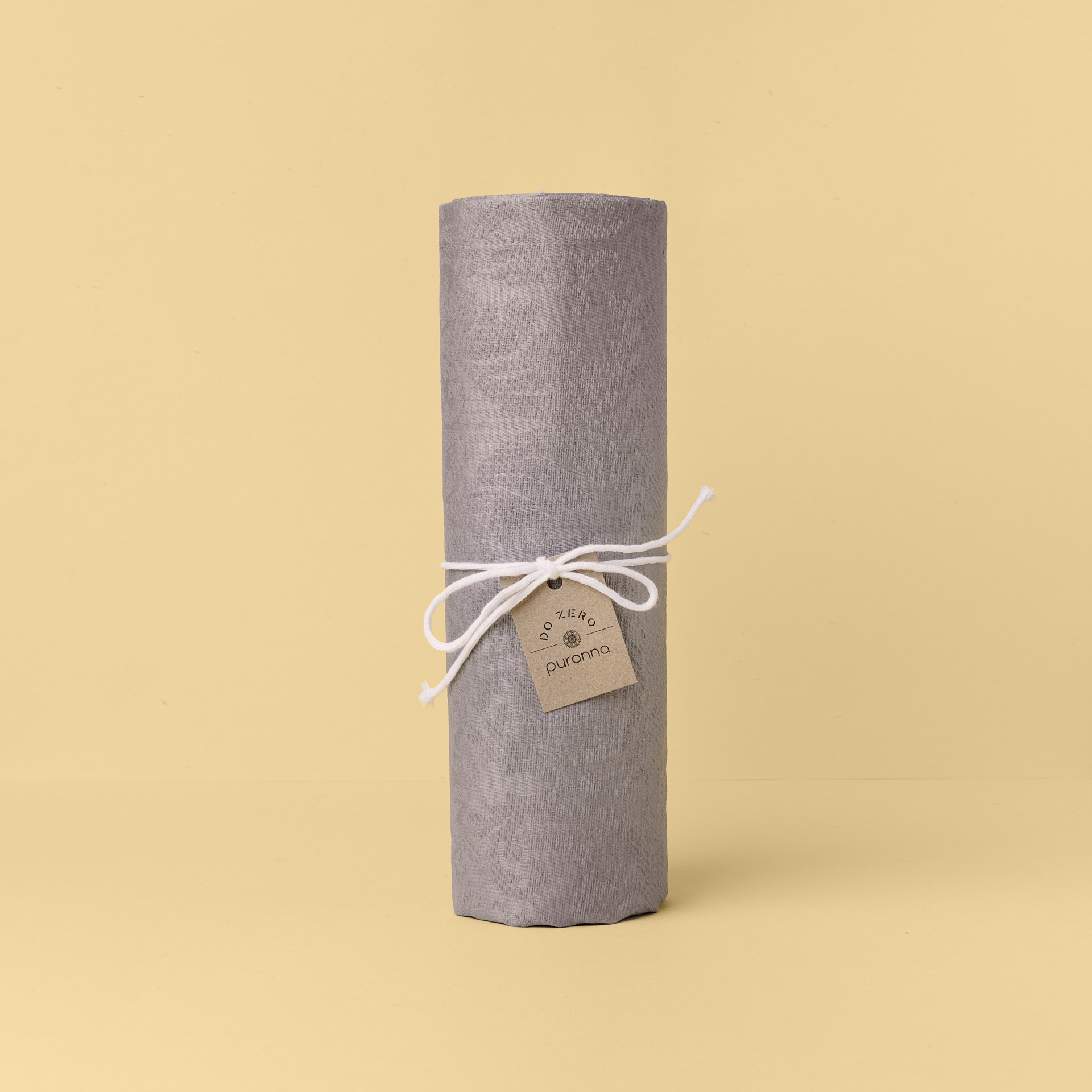 Rolo de tecido cinzento com etiqueta aurora amarrada por cordão branco