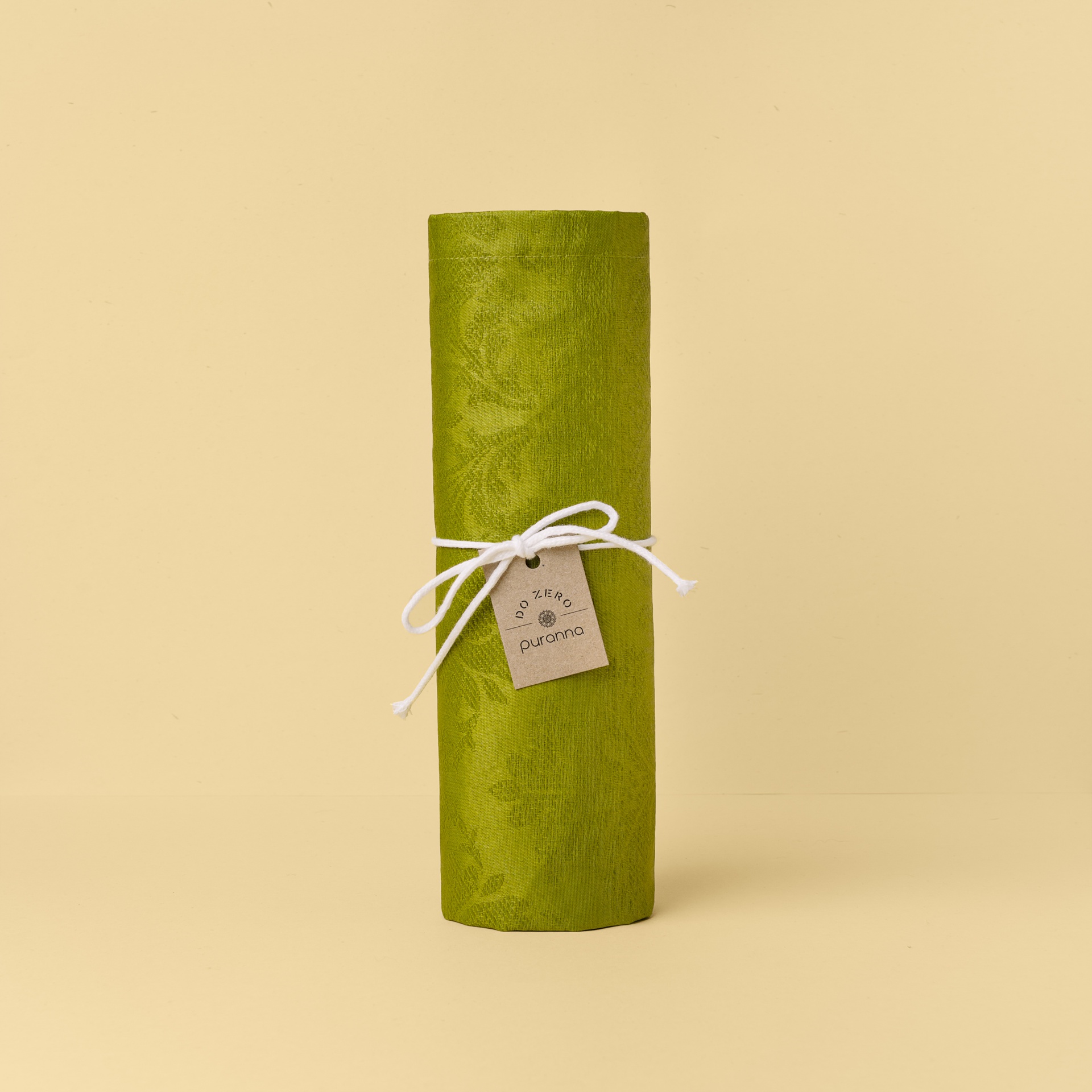 Rolo de tecido verde com padrão floral e etiqueta amarrada com cordão branco