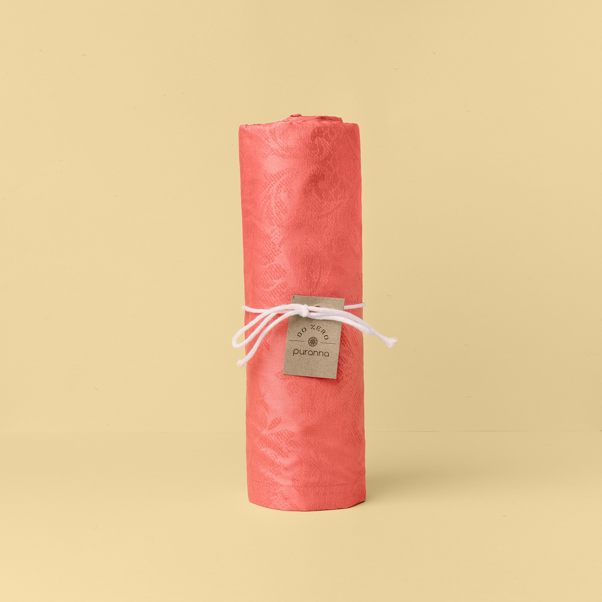 toalha coral enrolada com rótulo e cordão branco