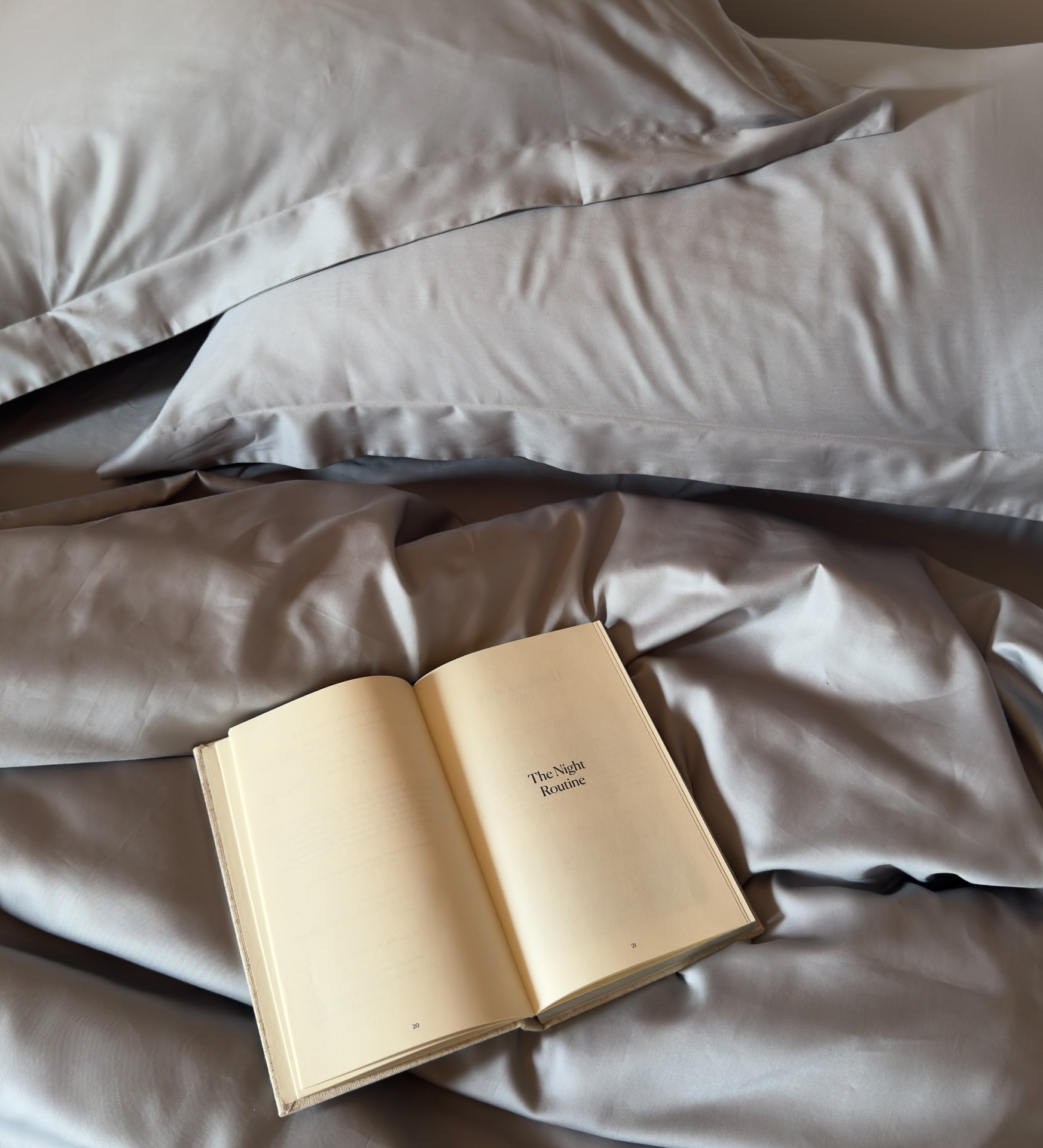 Lençóis cinza com livro aberto em cima