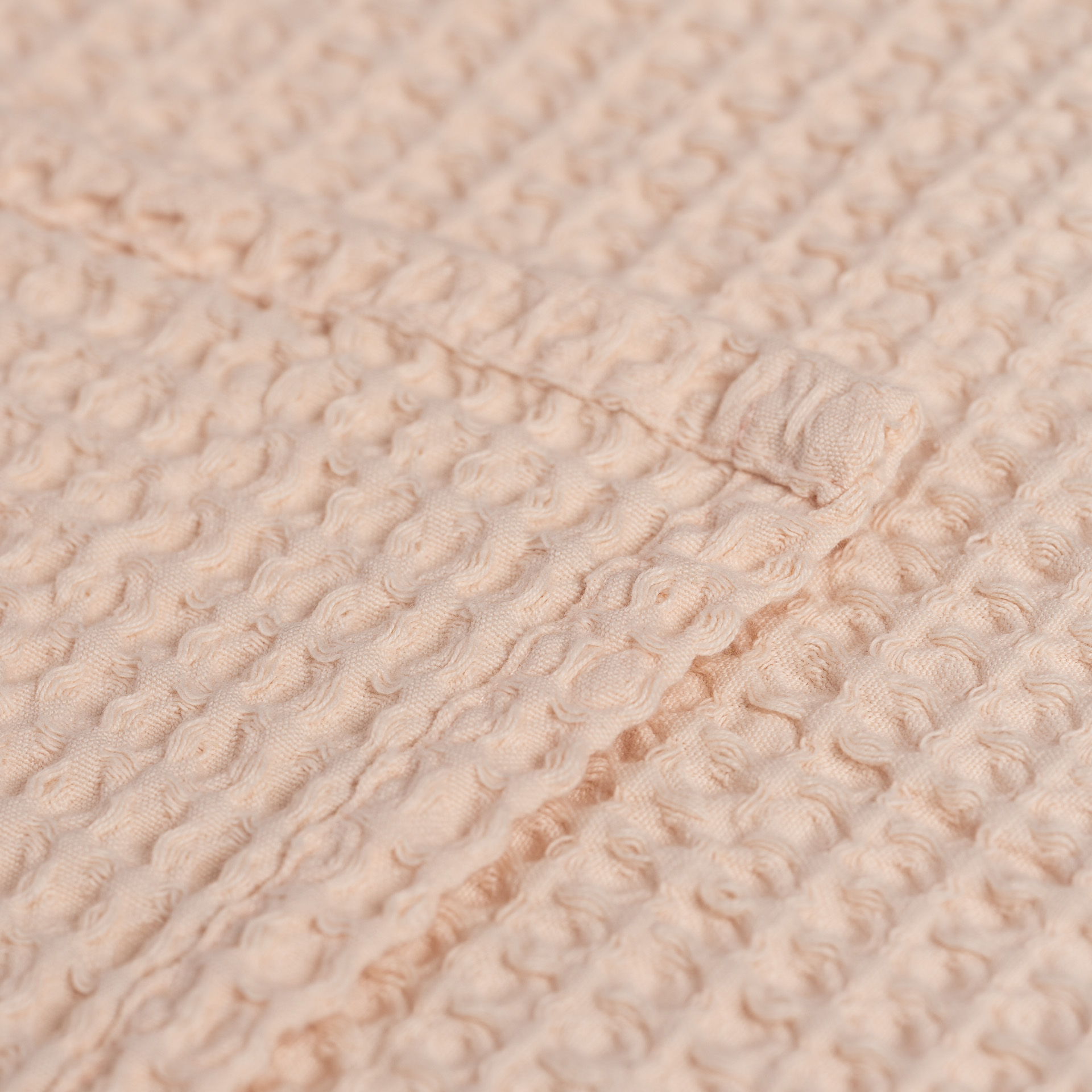 Tecido bege com textura em relevo e botão forrado