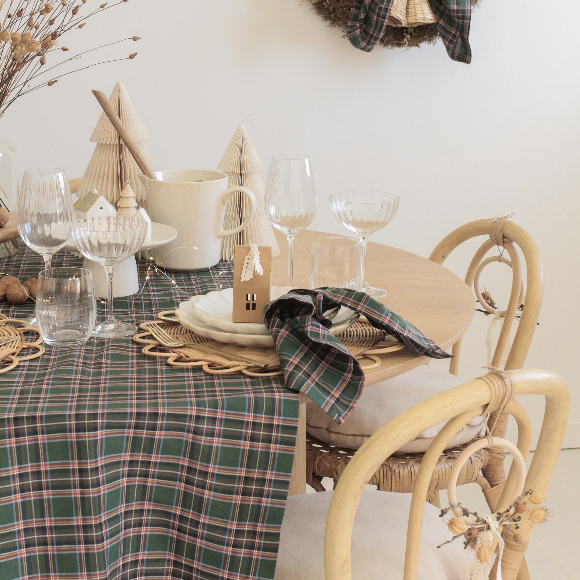 Mesa de madeira decorada com pratos, guardanapo xadrez, taças de vidro e cadeira de madeira com assento de palha