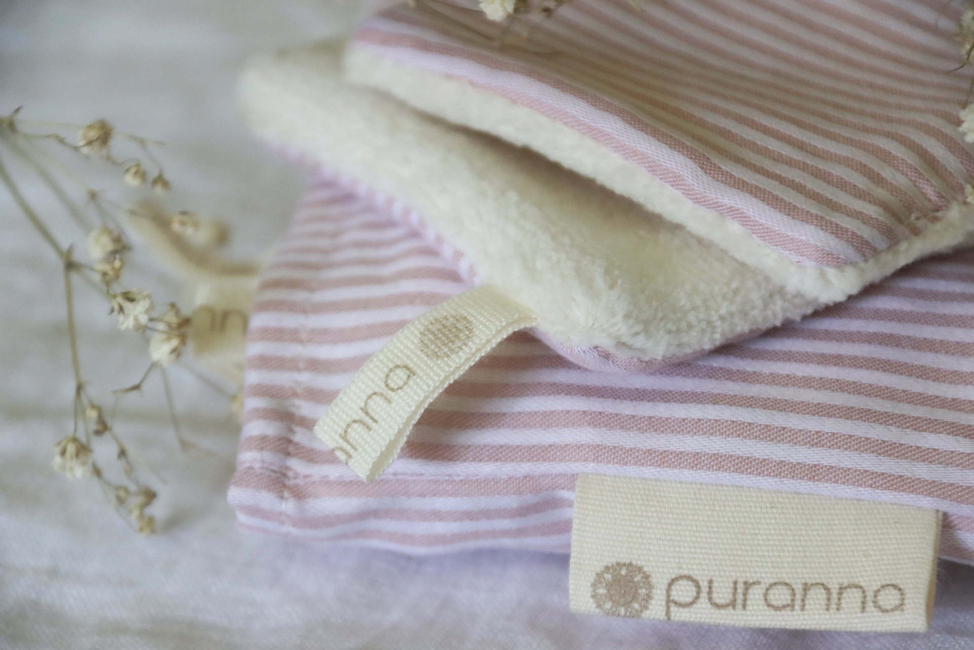 Produto tecido rosa e branco com interior peludo e etiquetas puranna