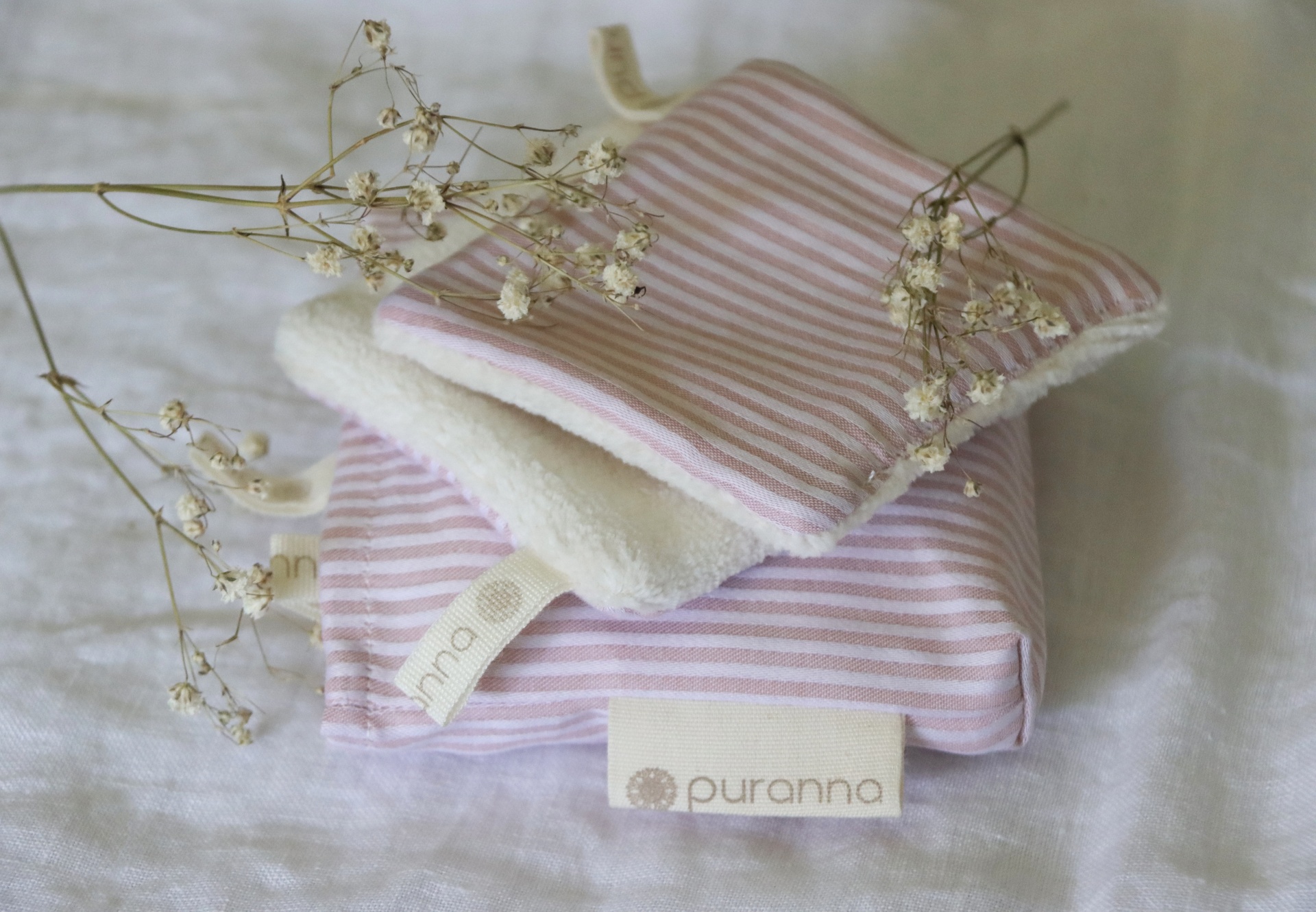 Conjunto de acessórios de tecido rosa às riscas com interior felpudo branco e etiquetas 'puranna'