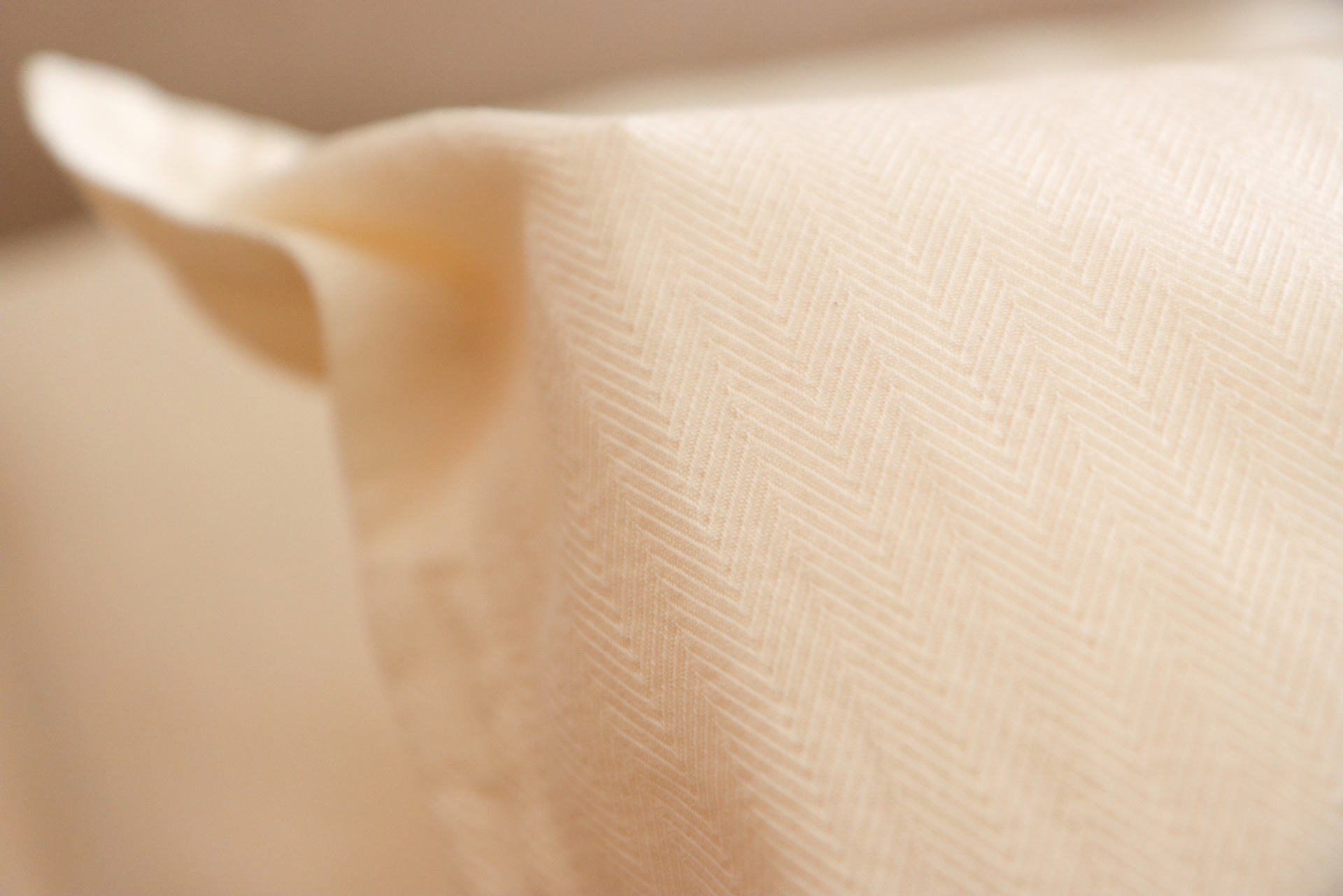 Tecido creme com padrão em espinha de peixe e dobra visível