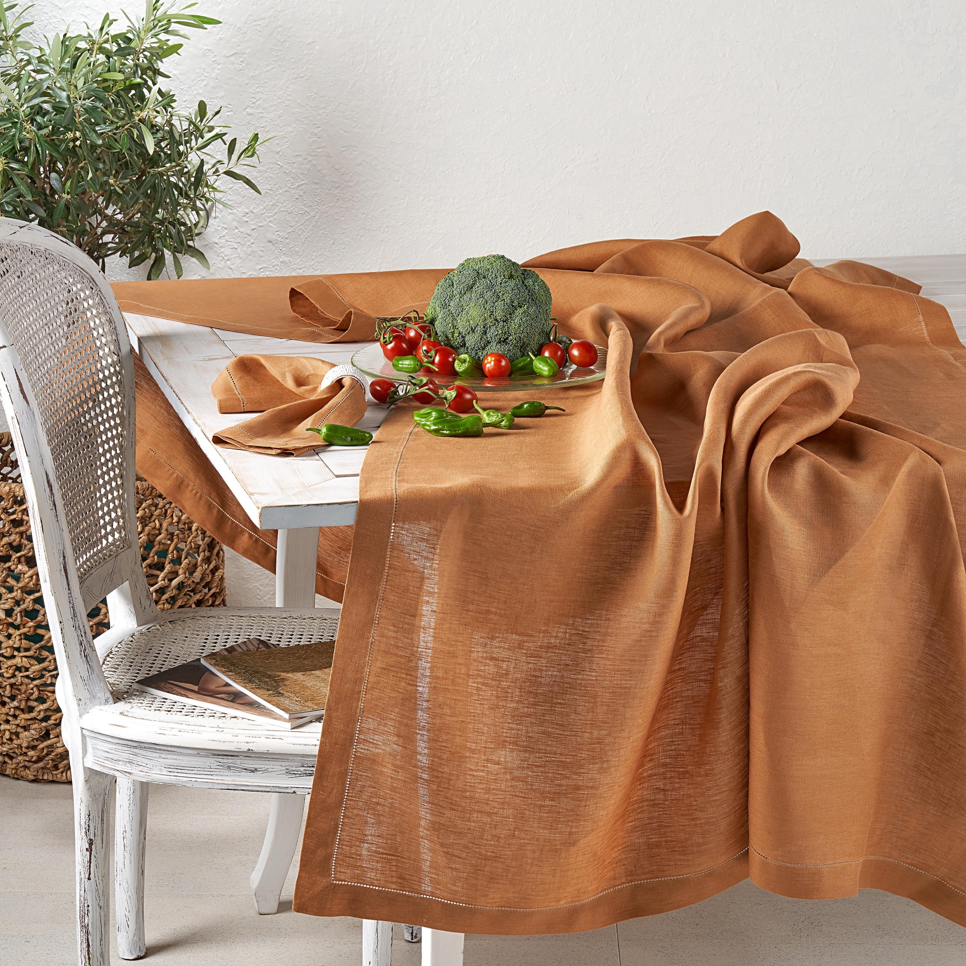 Toalha de mesa castanha clara sobre mesa branca de madeira com legumes frescos