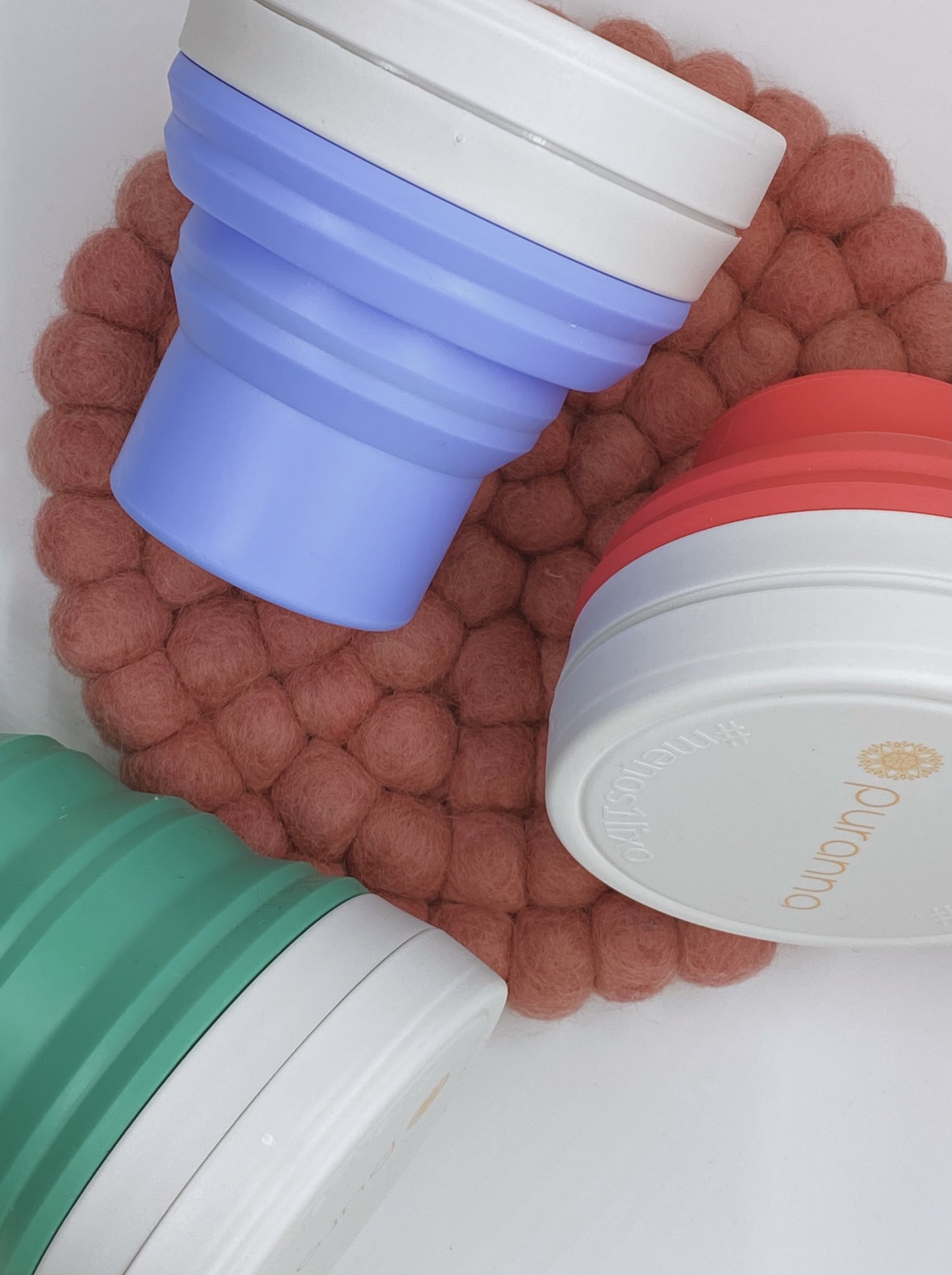 Copos dobráveis coloridos sobre descanso de copos rosa