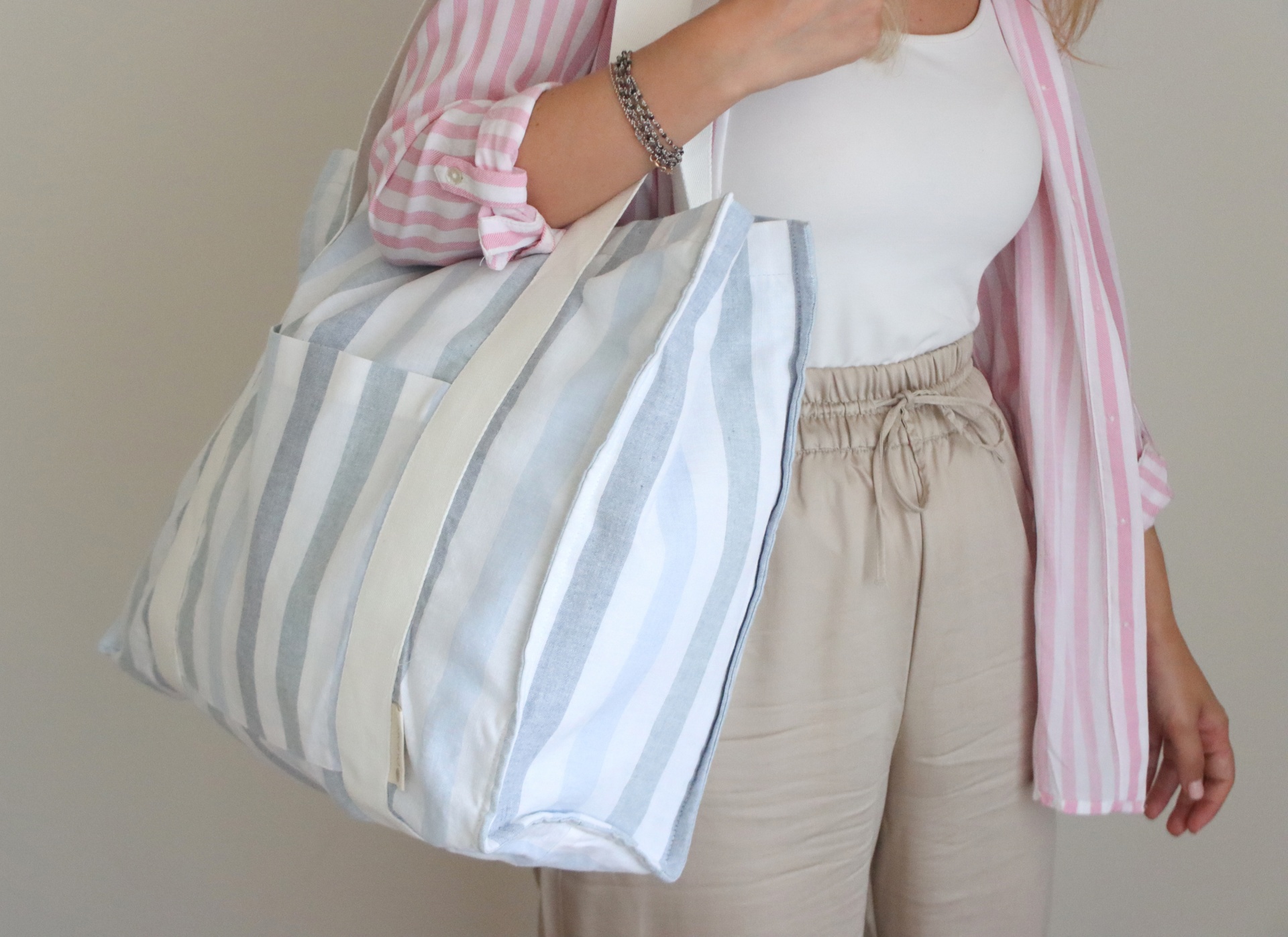 Mulher a segurar mala grande de tecido às riscas cinza e branco