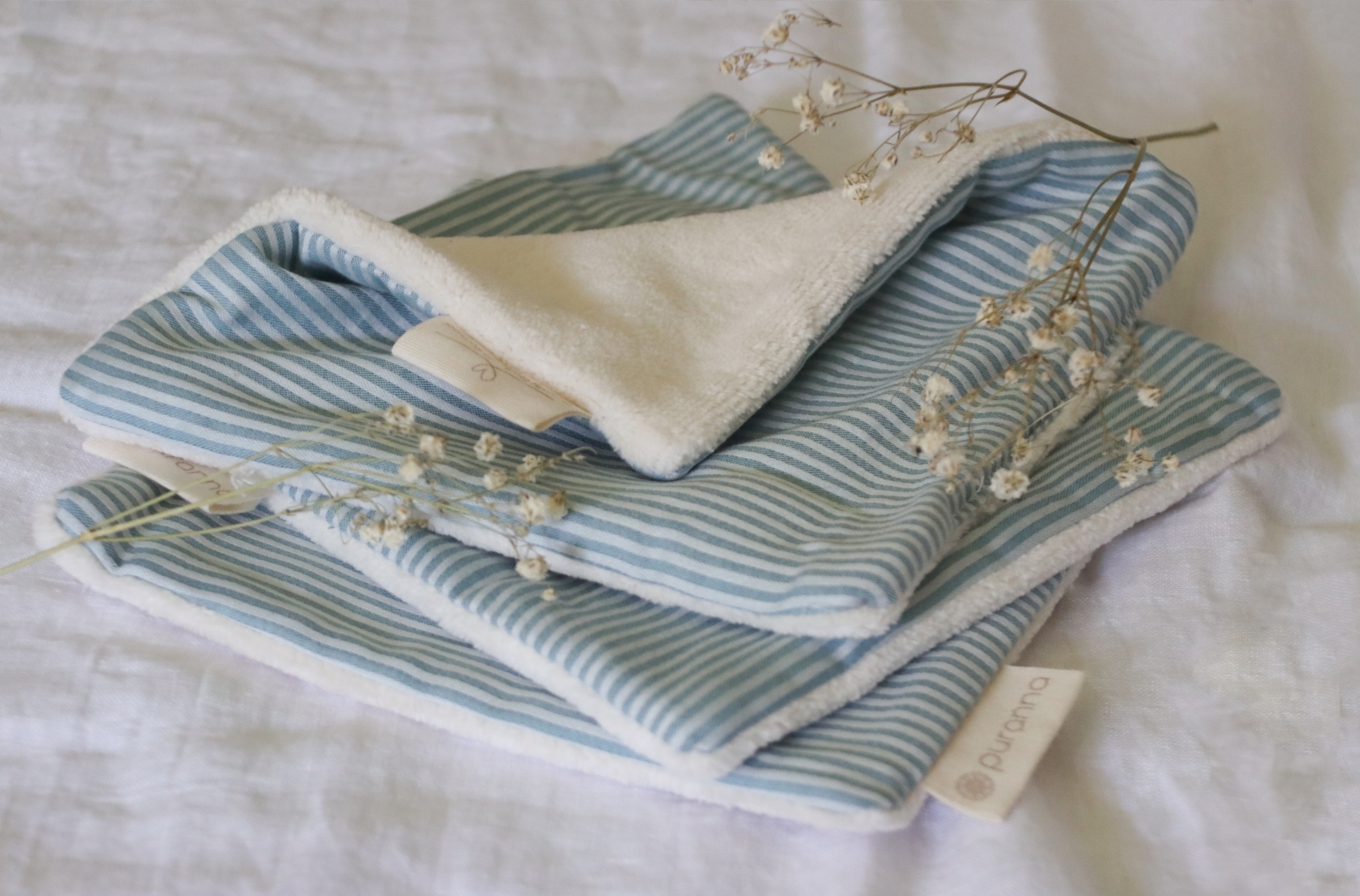 Toalha azul riscada com interior branco felpudo e raminhos secos