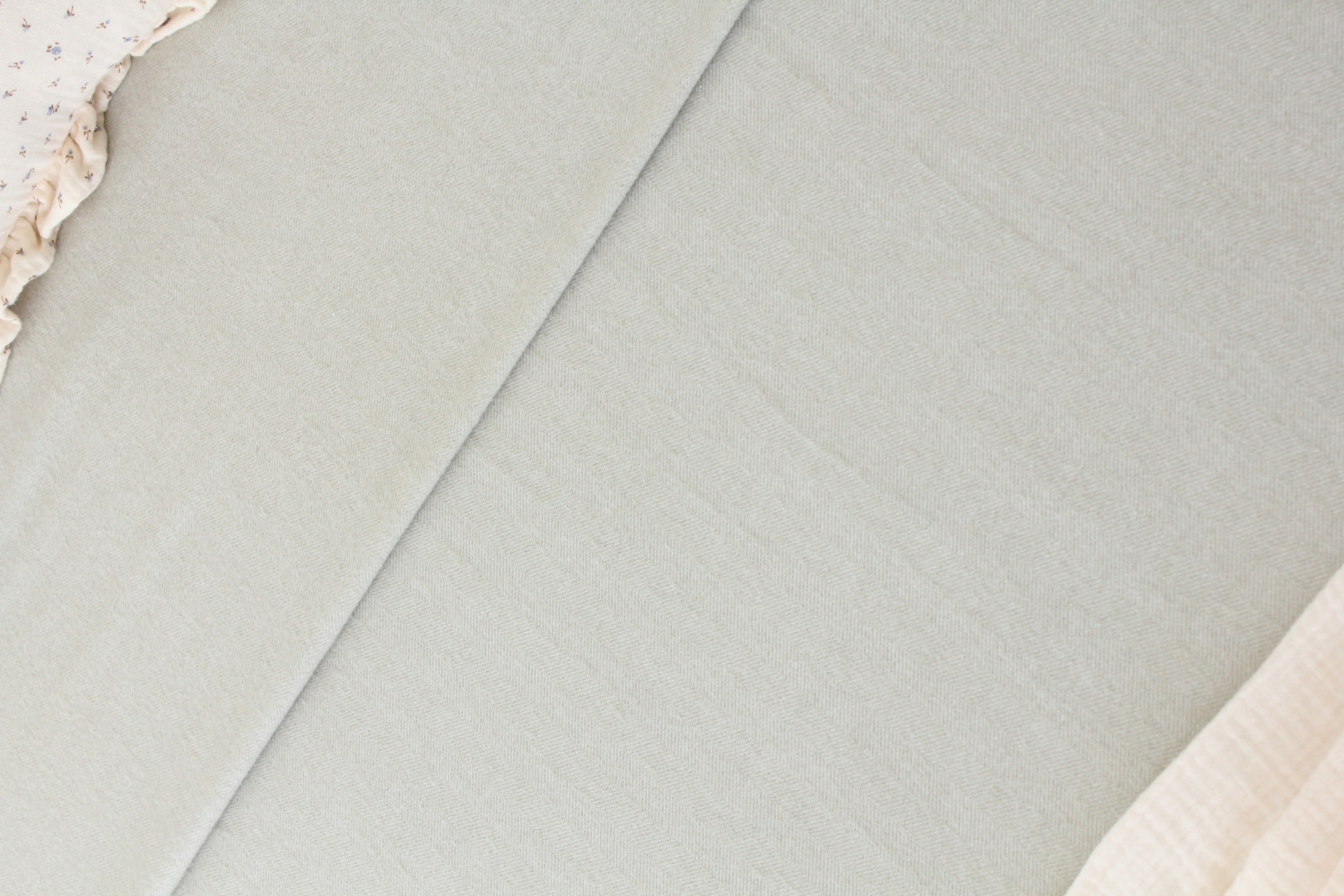 Capas de edredão cinza claro e bege sobre superfície clara com tecido bege ao redor