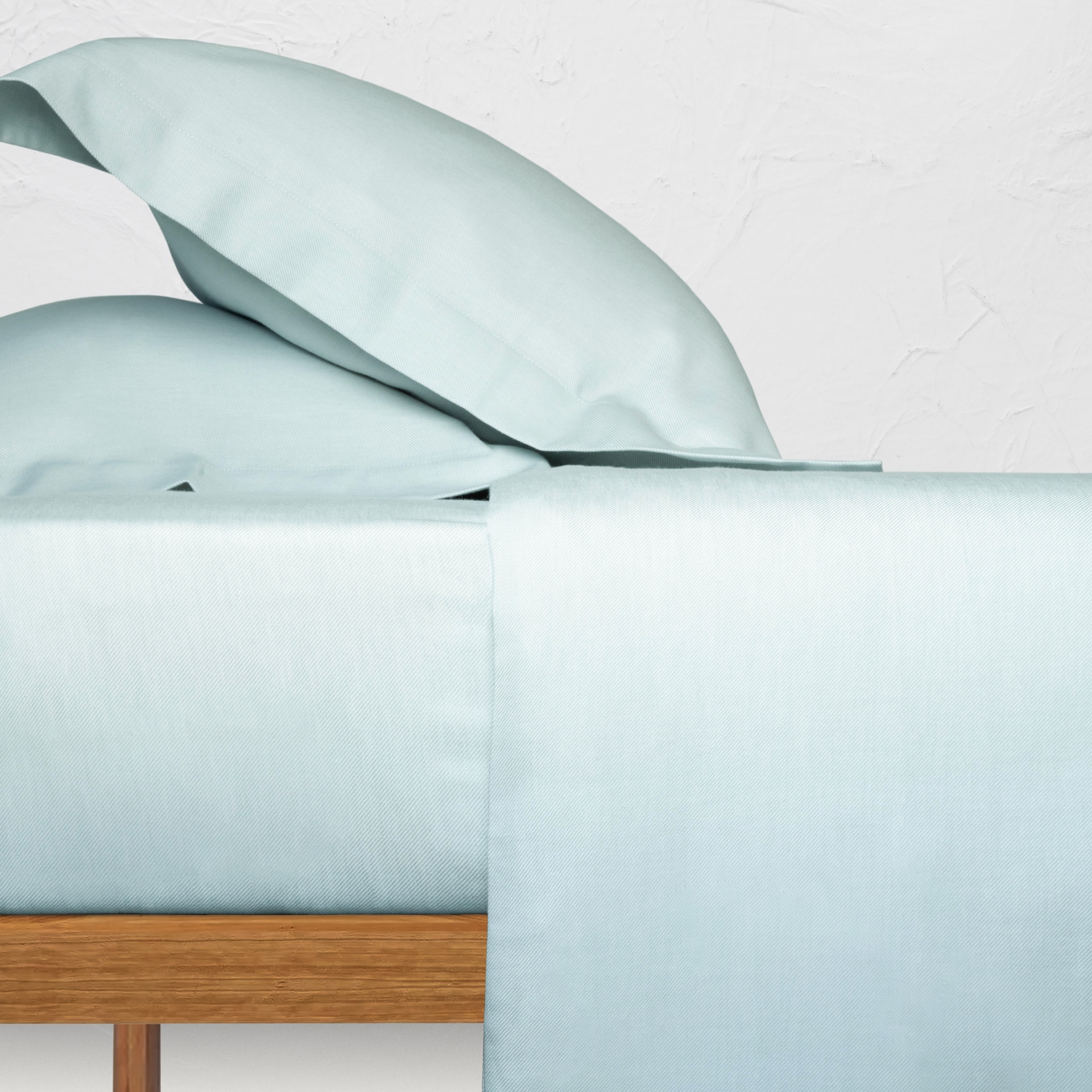 Roupa de cama azul claro numa cama com estrutura de madeira