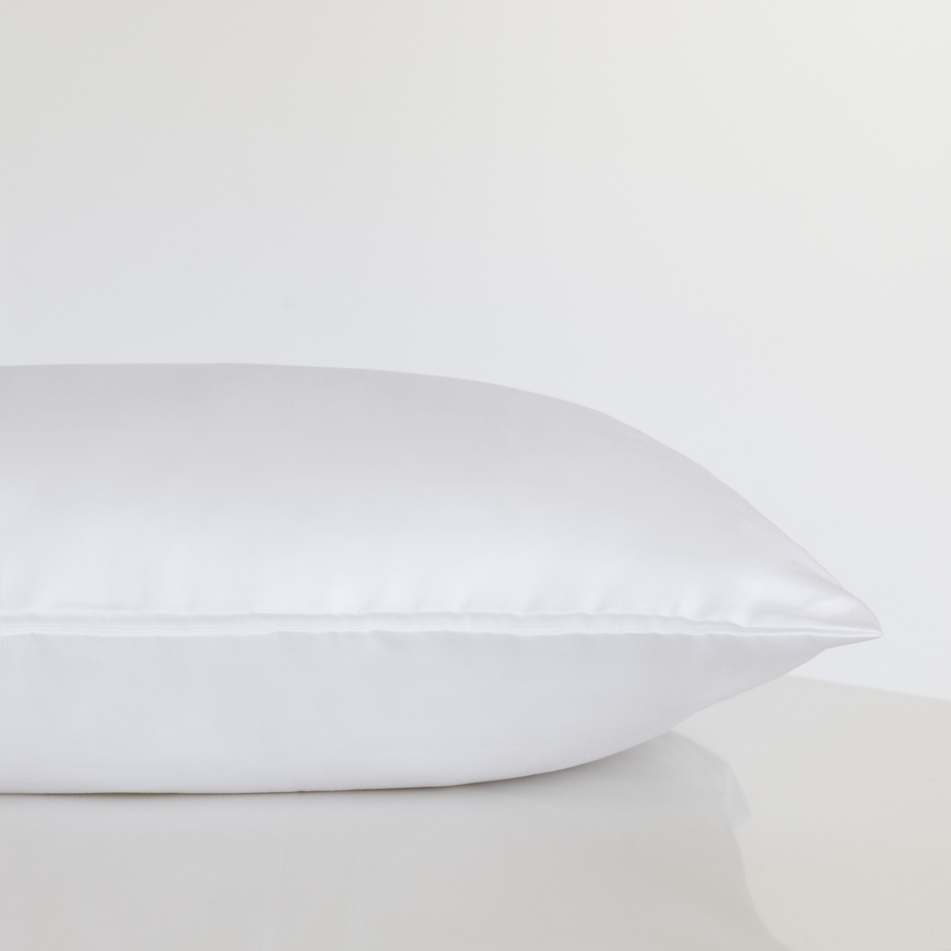 Travesseiro branco com capa lisa sobre superfície branca