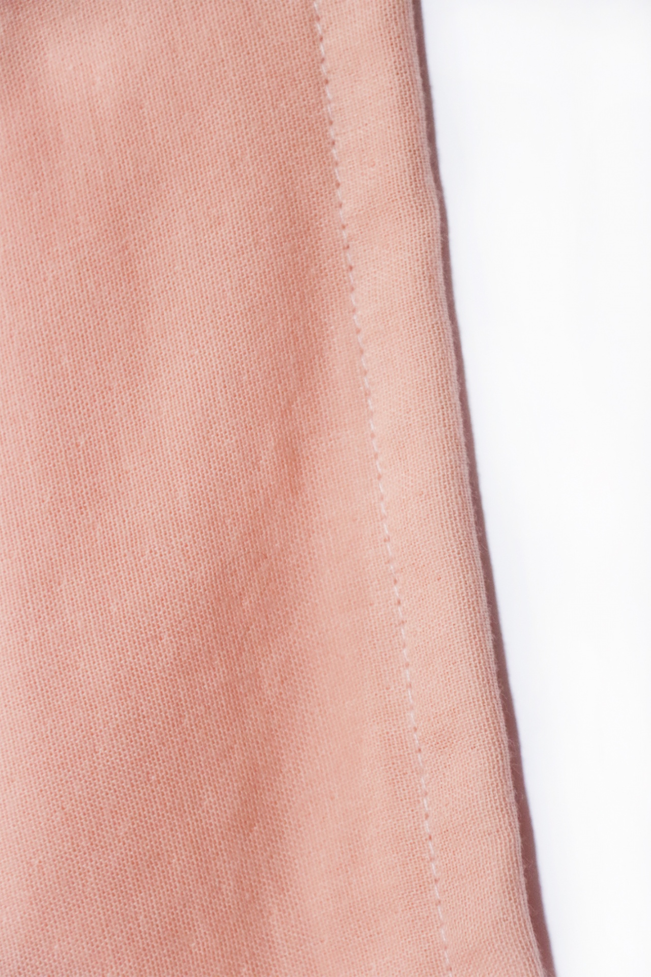 Close-up de tecido cor de salmão com costura e fundo branco