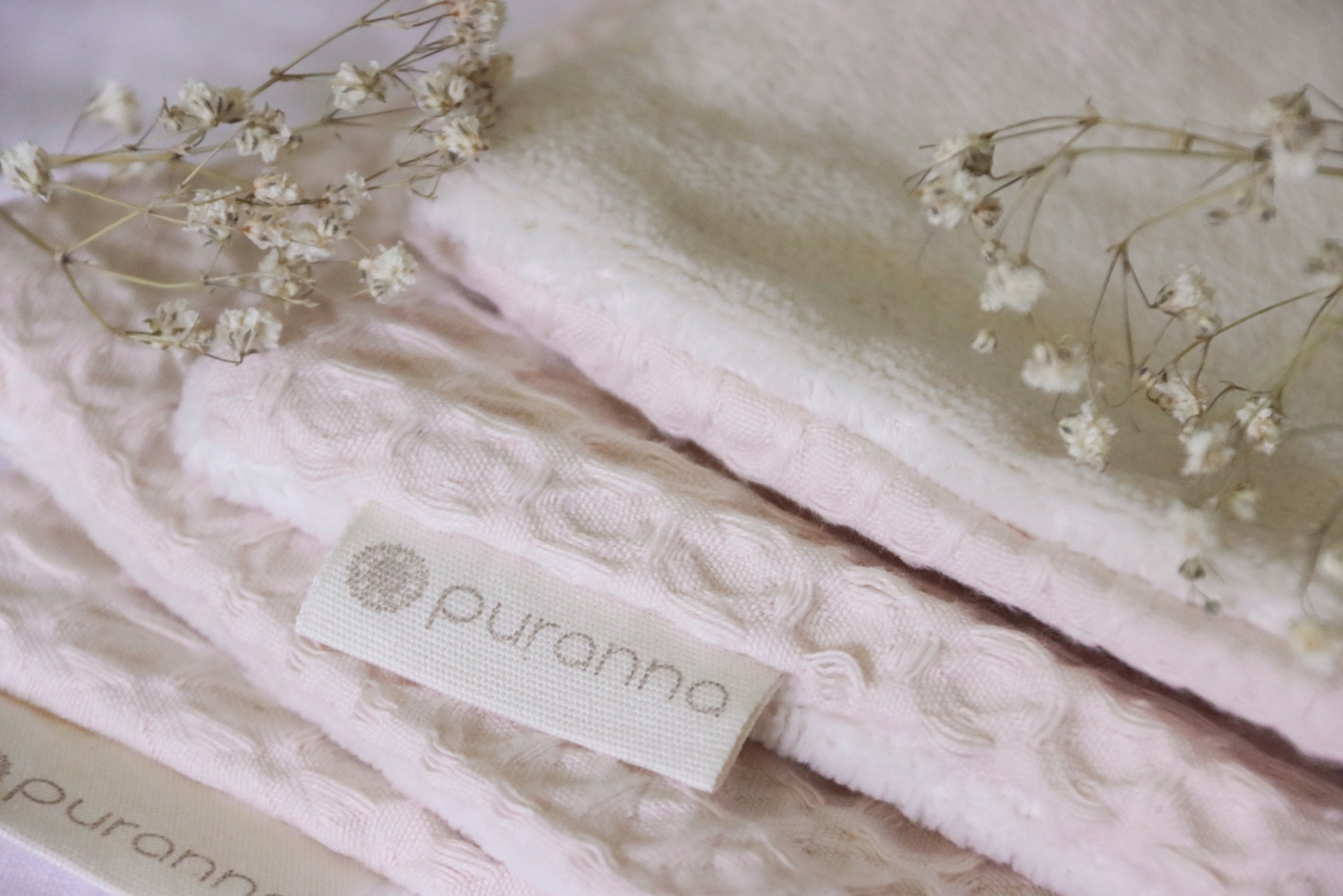 Mantas rosa claro e branca com etiqueta puranna e flores secas