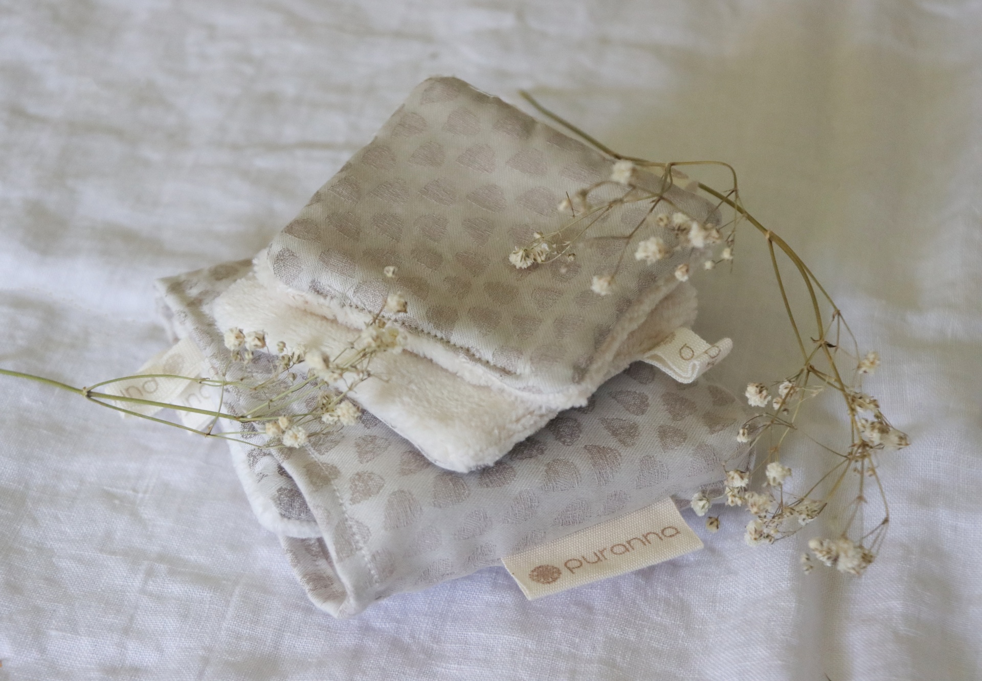 Dois pares de meias cinza com padrão de pontos e etiqueta purranna sobre tecido branco com flores secas