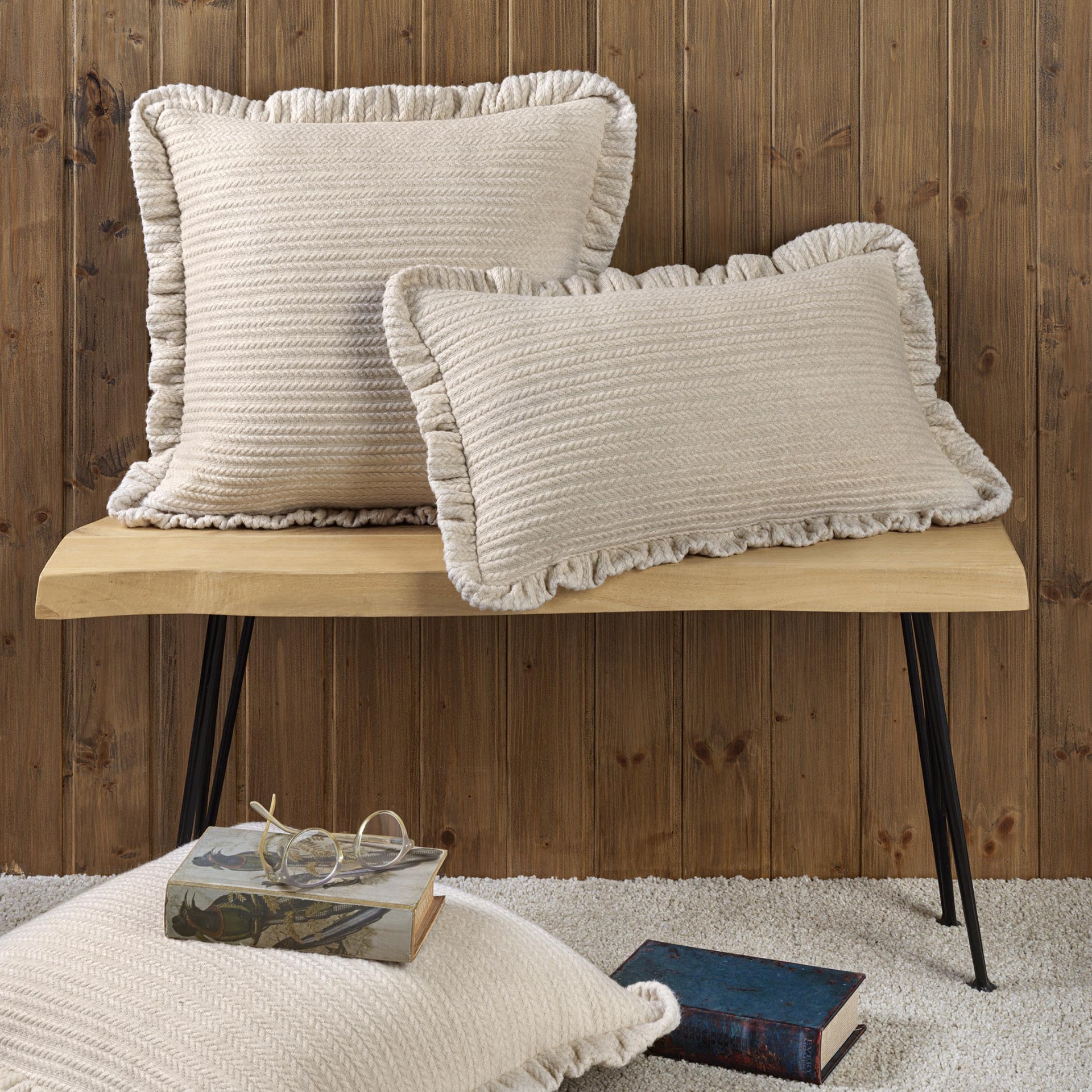 Almofadas decorativas bege em malha com franjas sobre banco de madeira