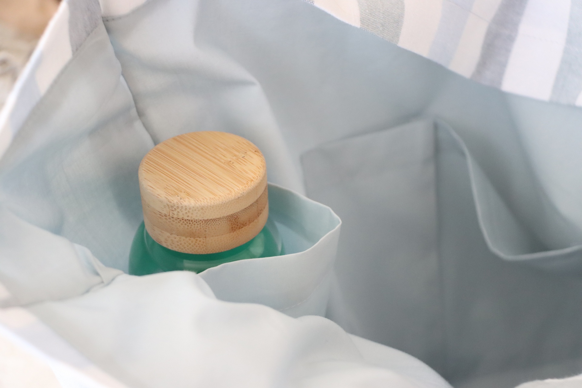 Saco cinza claro com garrafa verde de vidro e tampa de madeira