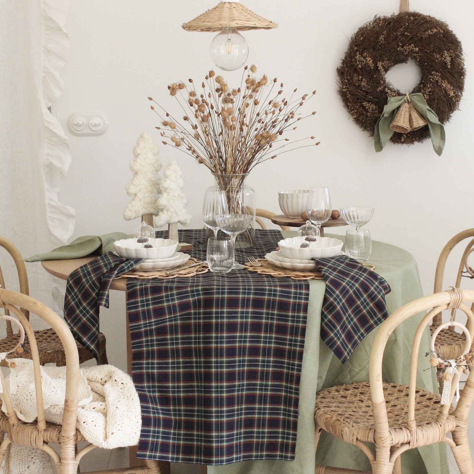 Mesa posta decorada para refeição com toalha verde, caminho xadrez, flores secas e velas em forma de árvore