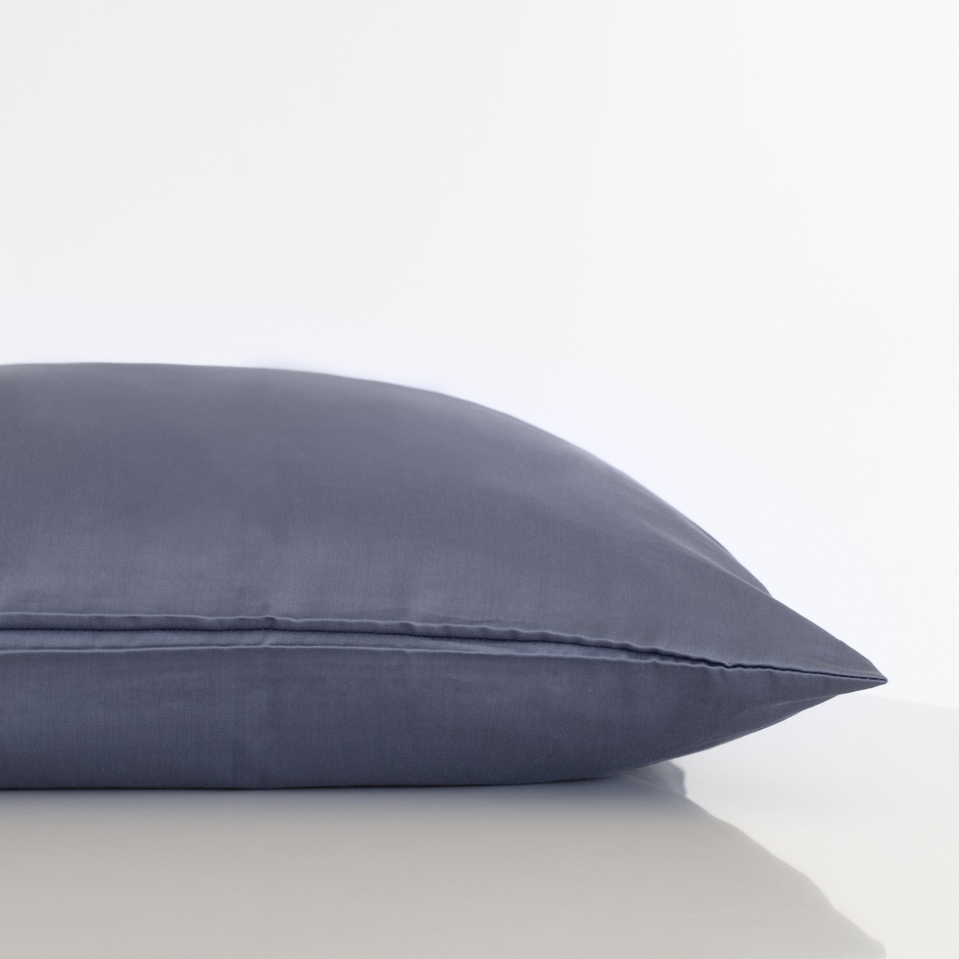 Almofada azul cinzento sobre superfície branca