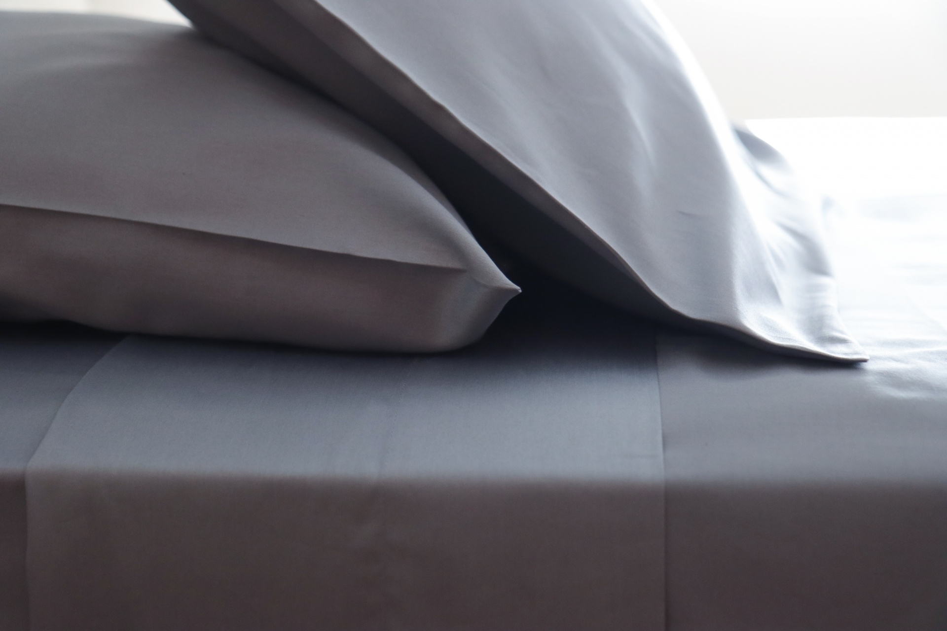 Jogo de cama cinzento com fronhas e lençol liso