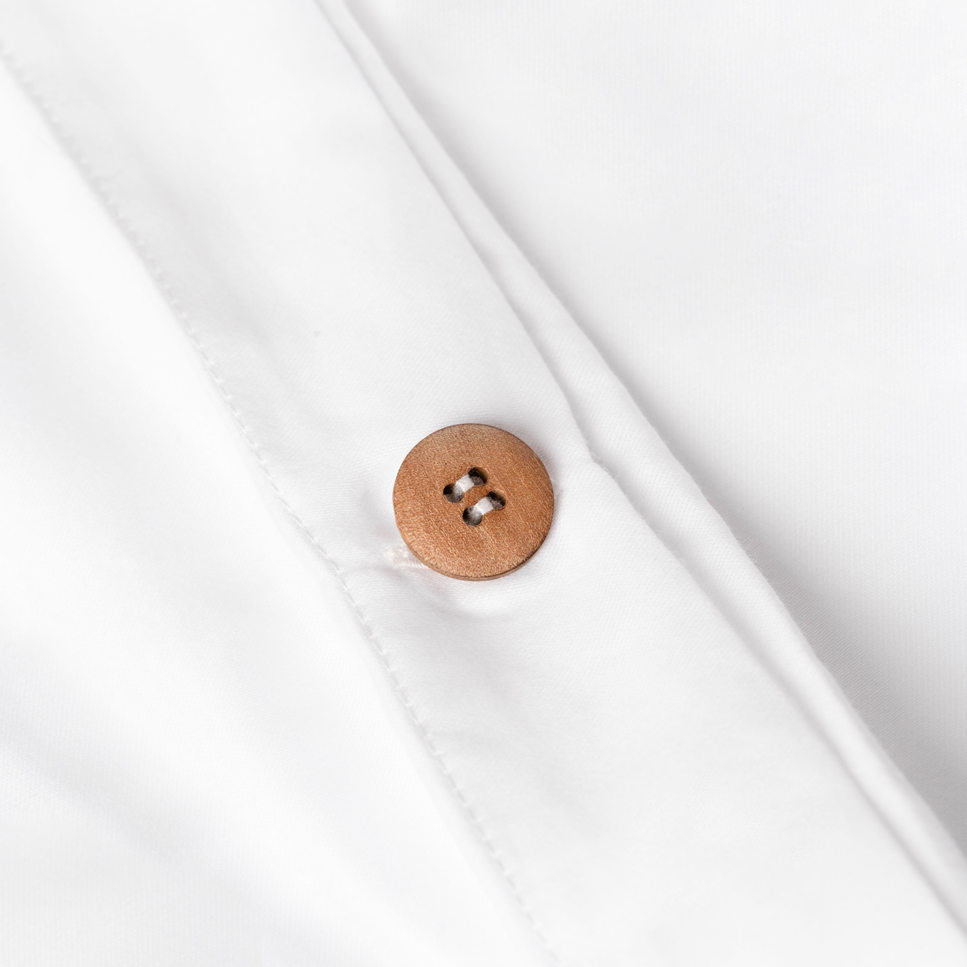 Botão de madeira castanha em tecido branco liso