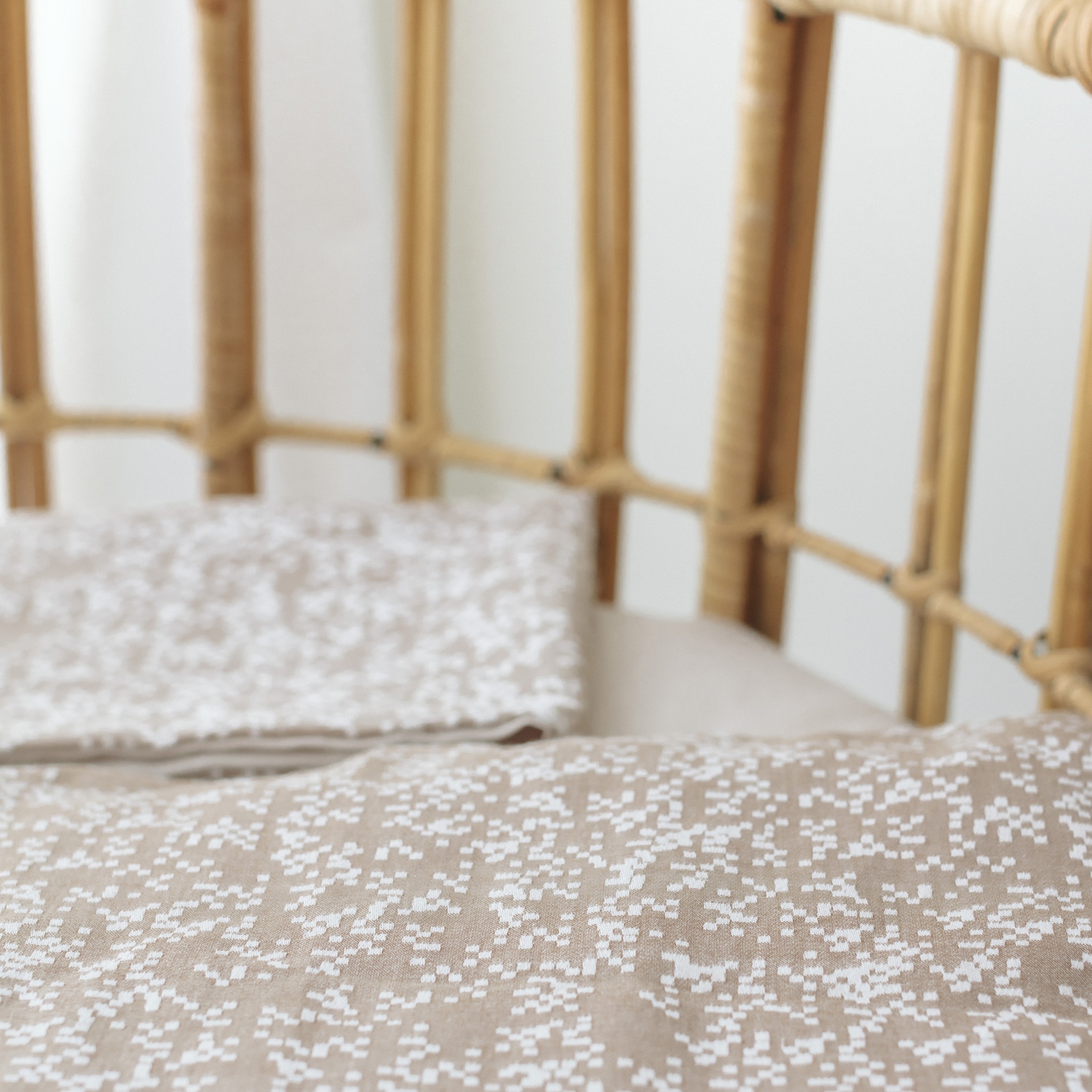 Inclusivos de cama bege com padrão branco sobre cama com estrutura de vime natural